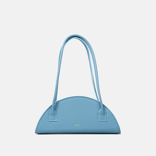 Półokrągła błękitna torba skórzana damska marki Taksuba z długimi uchwytami na ramię i złotym logo na przodzie.