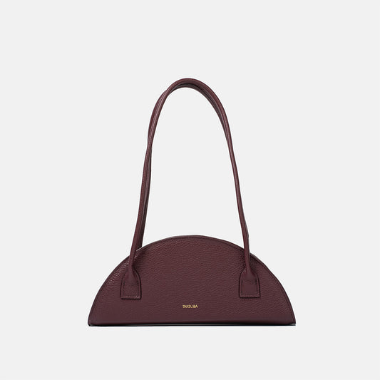 Półokrągła bordowa torba skórzana damska marki Taksuba z długimi uchwytami i złotym logo na środku frontu.