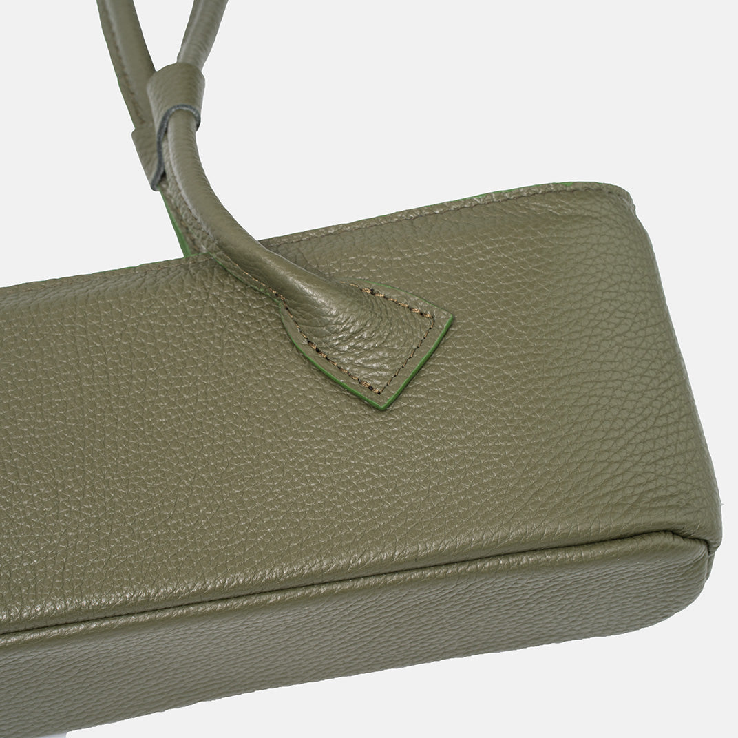 Detal zielonej torby skórzanej damskiej – mocowanie rączki z widocznym przeszyciem i fakturą skóry.