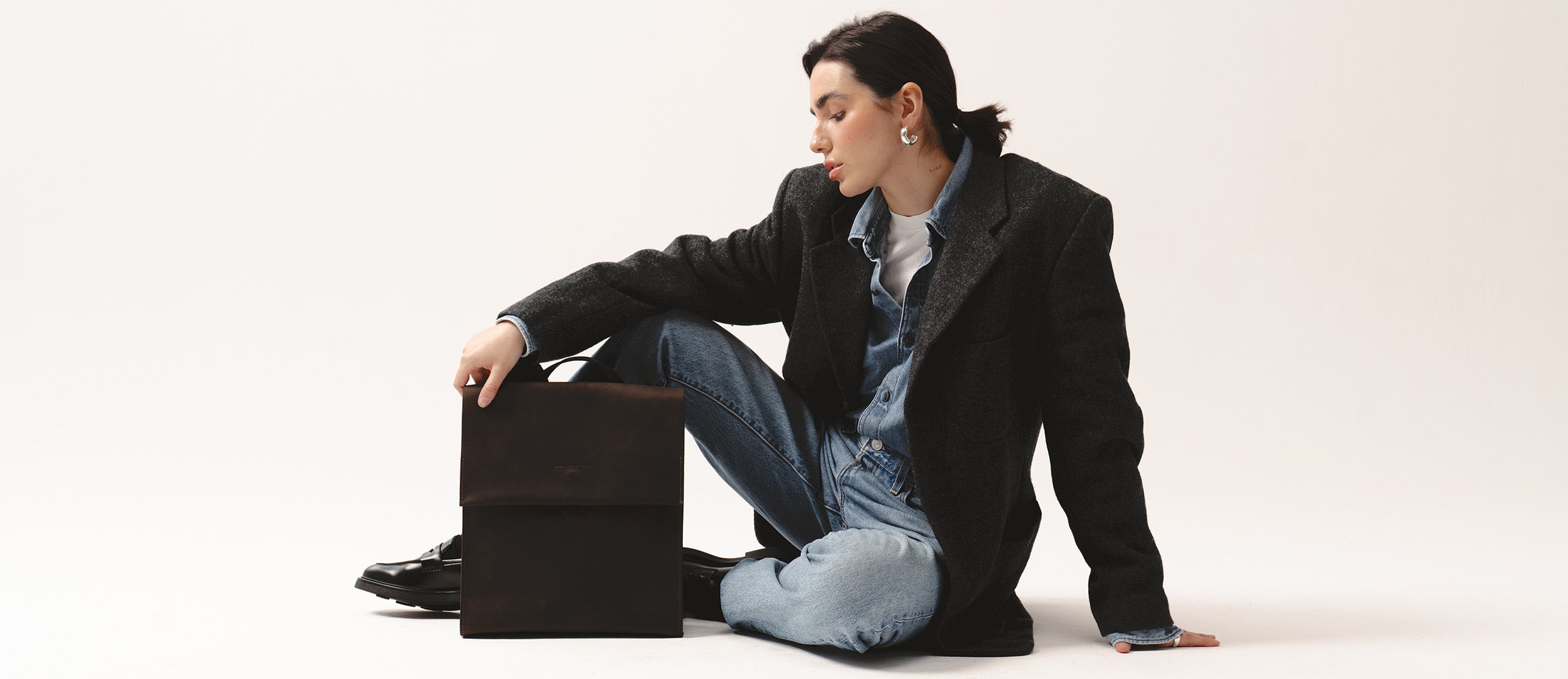 Modelka w casualowej stylizacji trzymająca skórzany plecak Backpack Fi ciemnobrązowy marki Taksuba