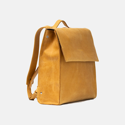 Żółty skórzany plecak Taksuba w widoku z boku, z klapą, uchwytem i regulowanymi szelkami, minimalistyczny design.
