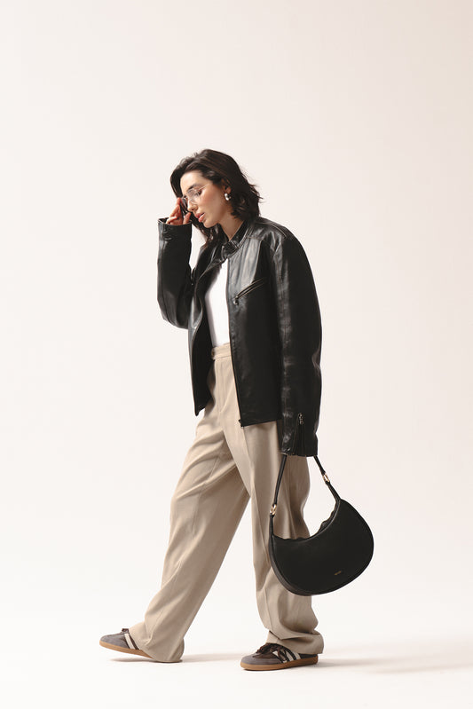 Skórzana torebka Hedera czarna crossbody na ramię, stylizacja z kurtką skórzaną i beżowymi spodniami