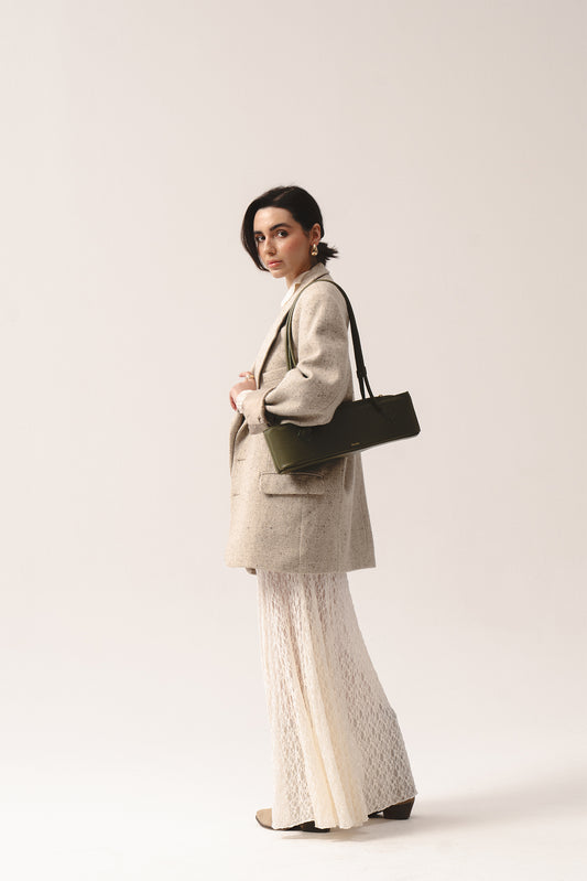 Torebka Teckelete w kolorze oliwkowym na ramieniu, stylizacja z beżowa marynarka i koronkową spódnicą