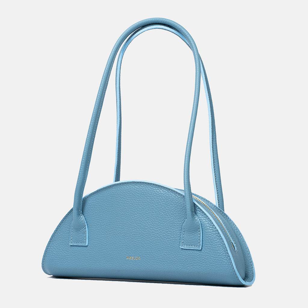 Błękitna torba skórzana damska marki Taksuba o półokrągłym kształcie, z fakturowanej skóry, z długimi uchwytami i złotym logo.