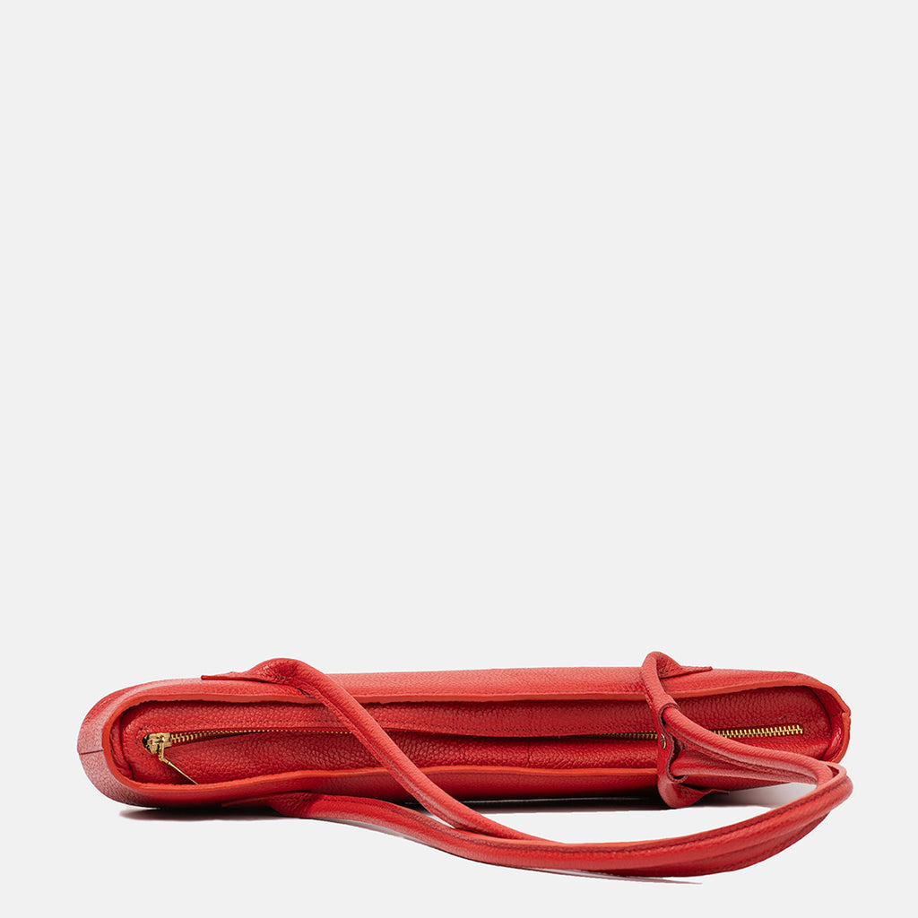 Czerwona skórzana torebka Lamina w widoku z góry, prezentująca smukły kształt, złoty zamek i regulowane paski, minimalistyczny design.
