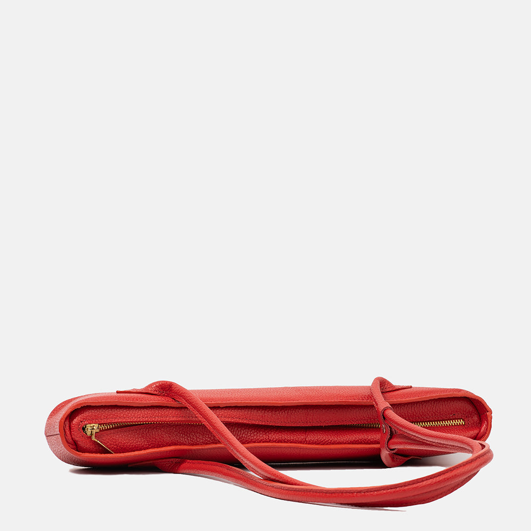 Czerwona skórzana torebka Lamina w widoku z góry, prezentująca smukły kształt, złoty zamek i regulowane paski, minimalistyczny design.