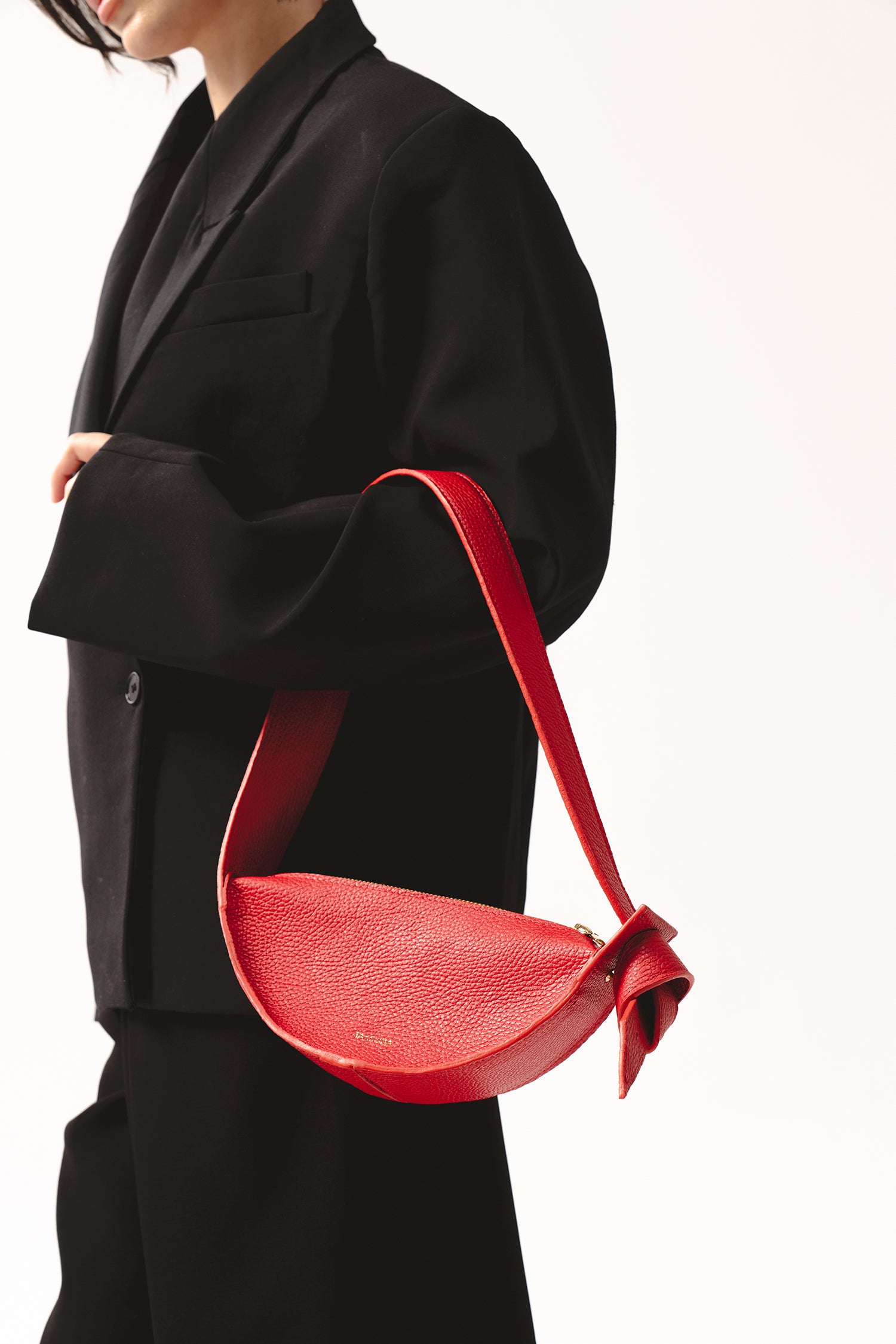 Skórzana czerwona torebka damska na ramię – półokrągła torba Eclipse S z miękkiej włoskiej skóry, detal z węzłem na pasku, widok z bliska