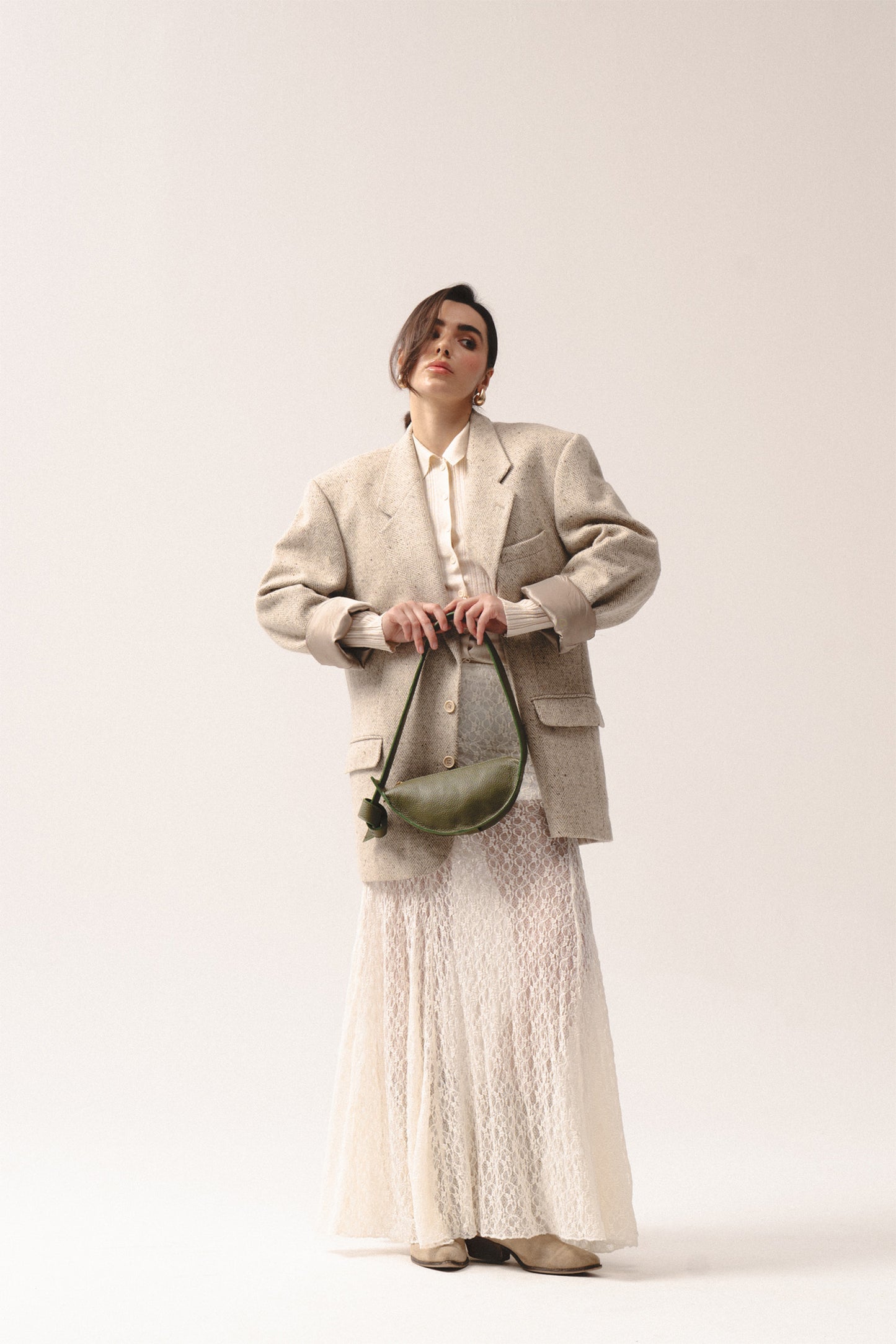 oliwkowozielona skórzana torebka półksiężycowa trzymana w dłoniach – olive green crescent leather handbag held in hands
