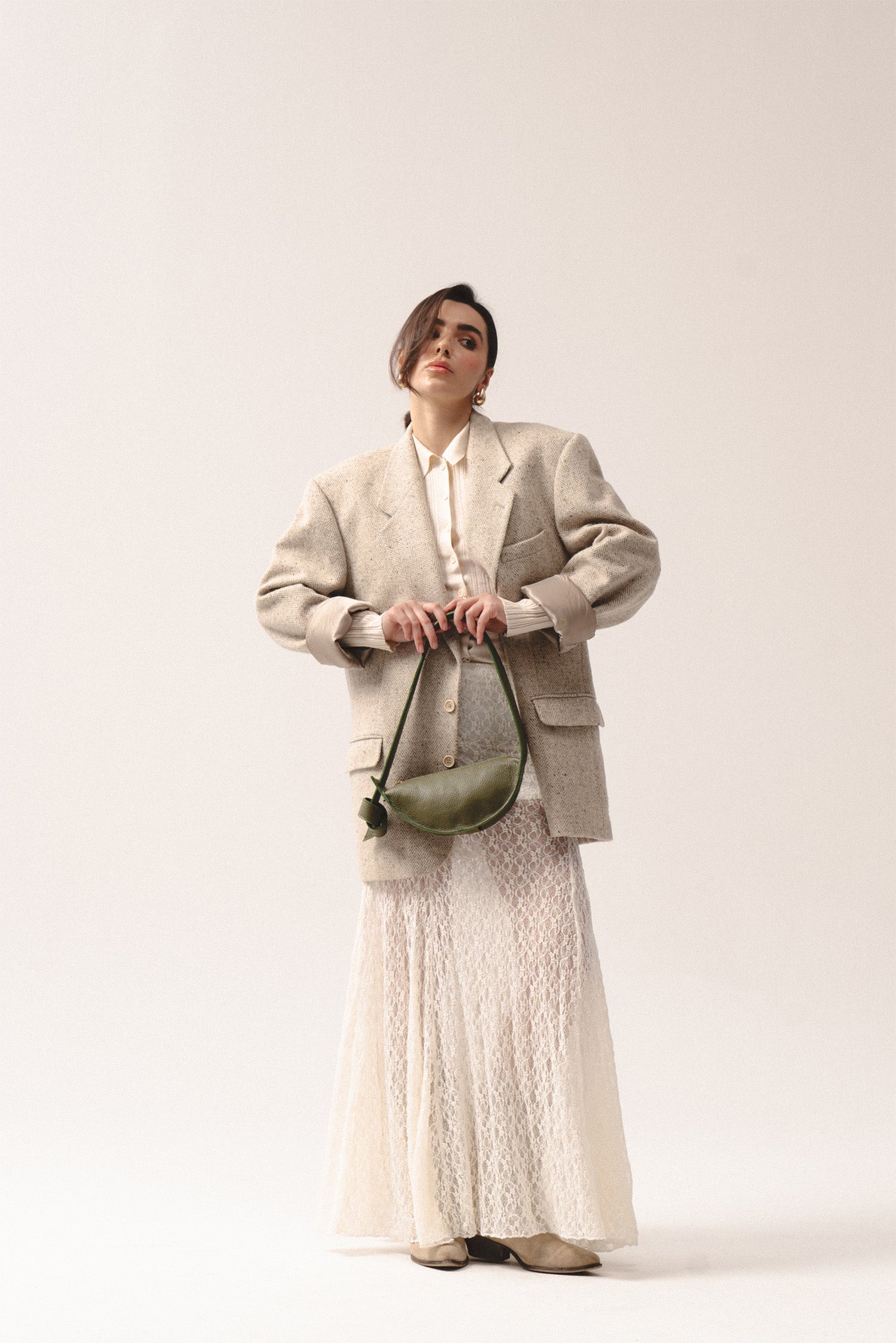oliwkowozielona skórzana torebka półksiężycowa trzymana w dłoniach – olive green crescent leather handbag held in hands