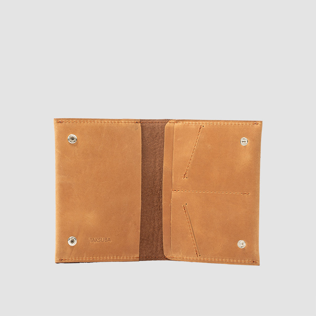 zdjęcie pomarańczowego portfela na paszport, otwarte, ukazujące przestronne wnętrze z miejscami na paszporty, karty i banknoty, z zatrzaskami, ręcznie wykonane w Polsce