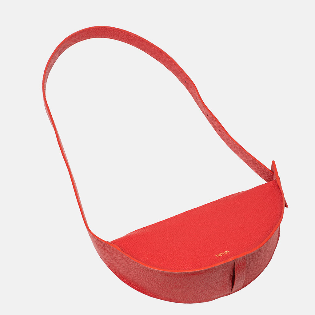 Front top view of the red Eclipse M leather handbag with rounded shape and wide strap