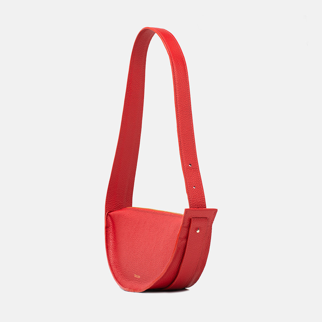 Side view of the red Eclipse M leather handbag with wide strap and textured leather