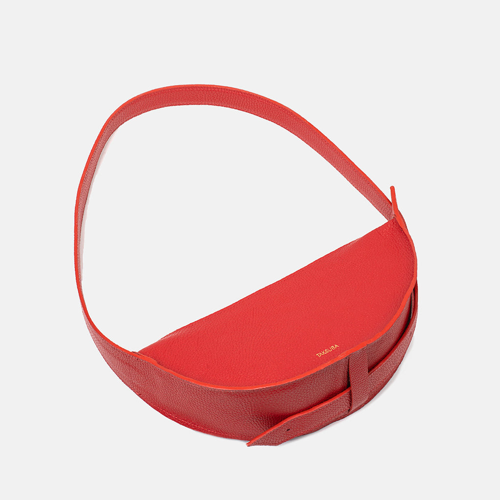Top view of the red Eclipse M leather handbag with crescent shape and strap detail