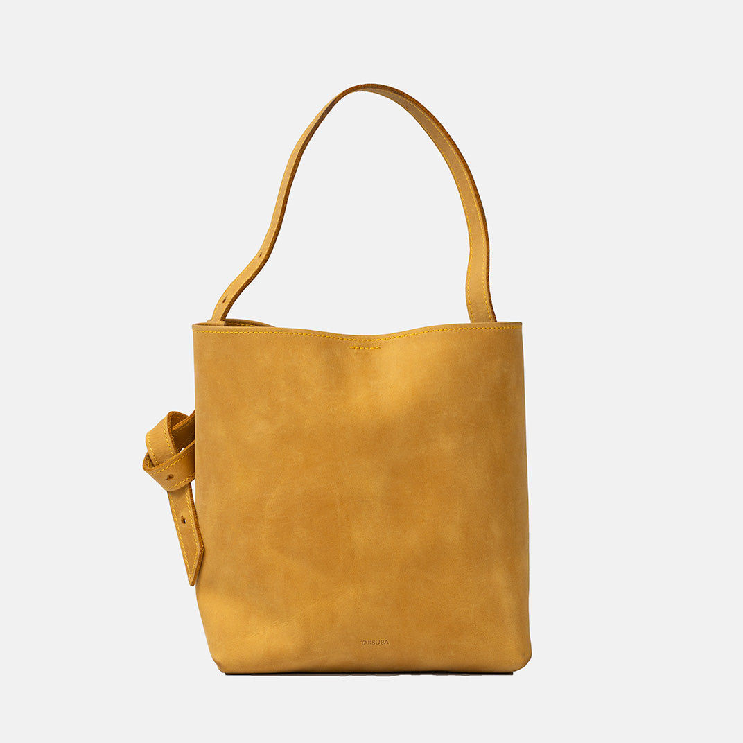 Żółta skórzana torba typu shopper tote z krótkim uchwytem i wiązanym paskiem marki Taksuba