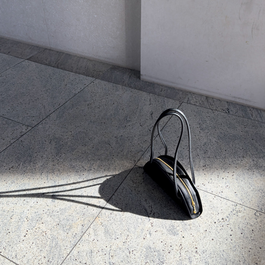 Torebka Amber w czerni, złote zamknięcia błyszczące w świetle słonecznym