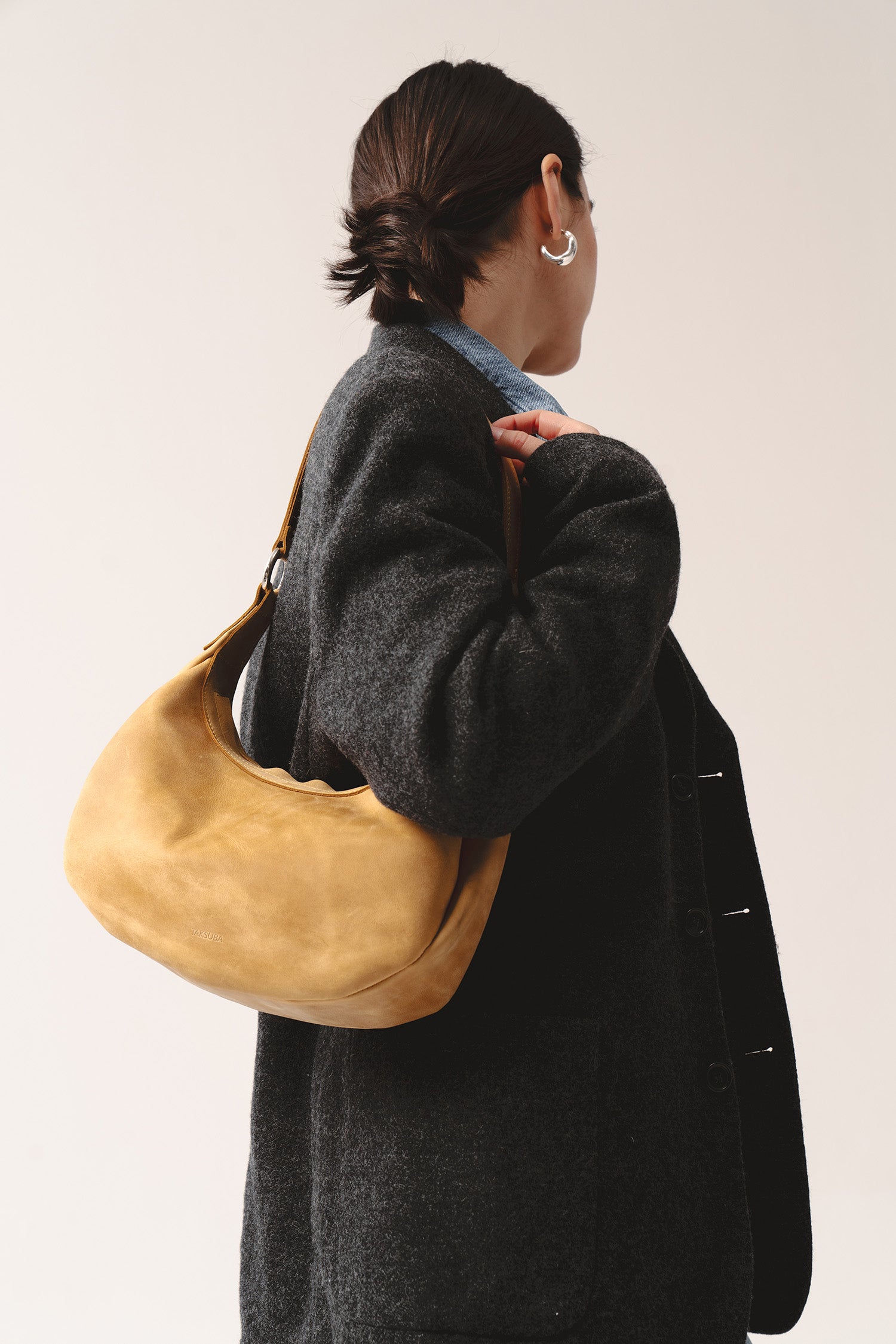 Skórzana torebka damska na ramię w kolorze żółtym – model Hedera z naturalnej skóry, noszona na ramieniu przez kobietę w czarnej marynarce.