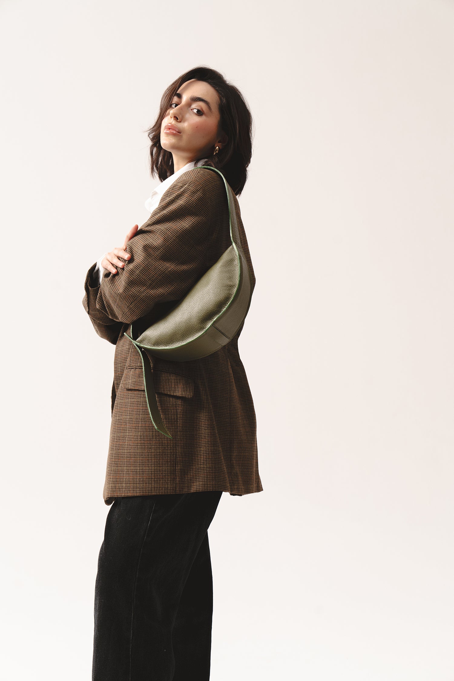 Skórzana torebka Eclipse M oliwkowa na ramieniu, stylizacja z marynarką w kratę i czarnymi spodniami