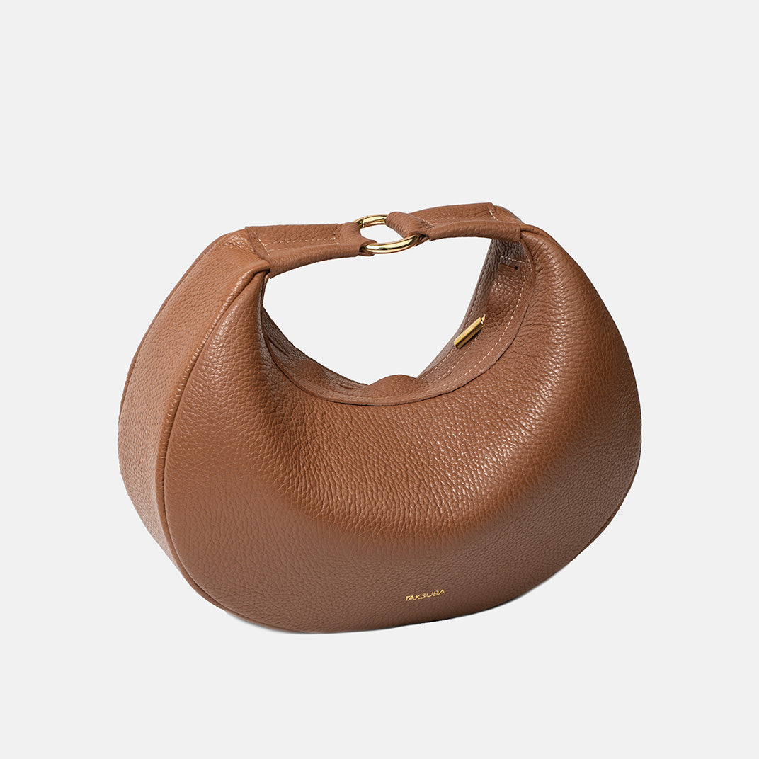 Brązowa skórzana torebka Hedera TAKSUBA z krótkim uchwytem na złotym kółku, widok z góry w lekkiej perspektywie