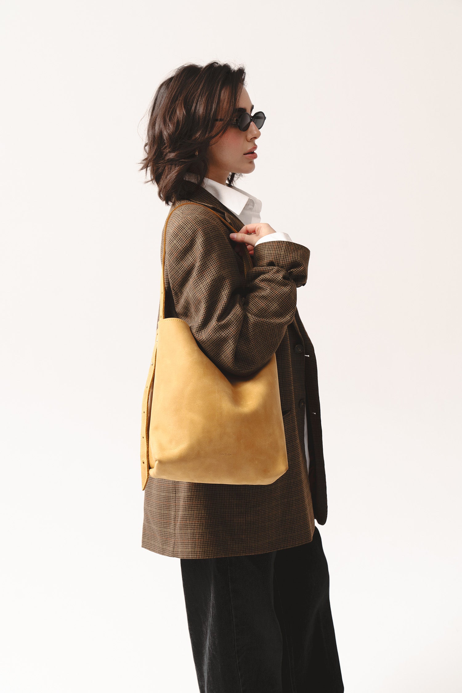 Żółta skórzana torebka shopper marki Taksuba noszona na ramieniu przez kobietę w brązowej marynarce