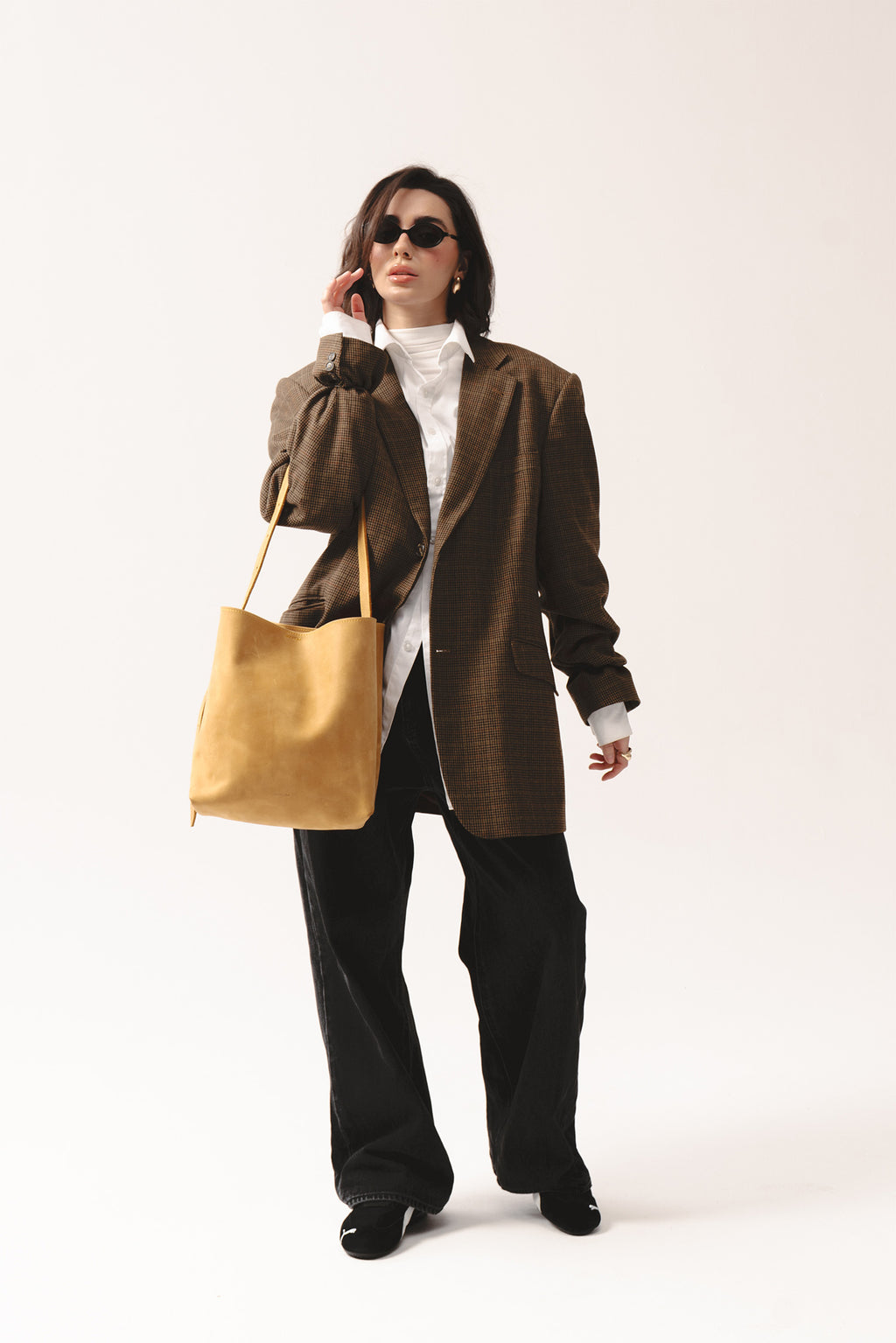 Żółta skórzana torebka shopper marki Taksuba noszona na ramieniu przez kobietę w okularach i brązowej marynarce