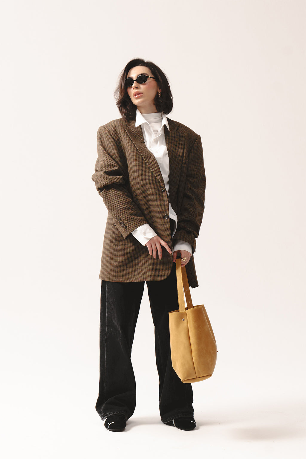 Żółta skórzana torebka shopper marki Taksuba trzymana w ręku przez kobietę w brązowej marynarce i okularach