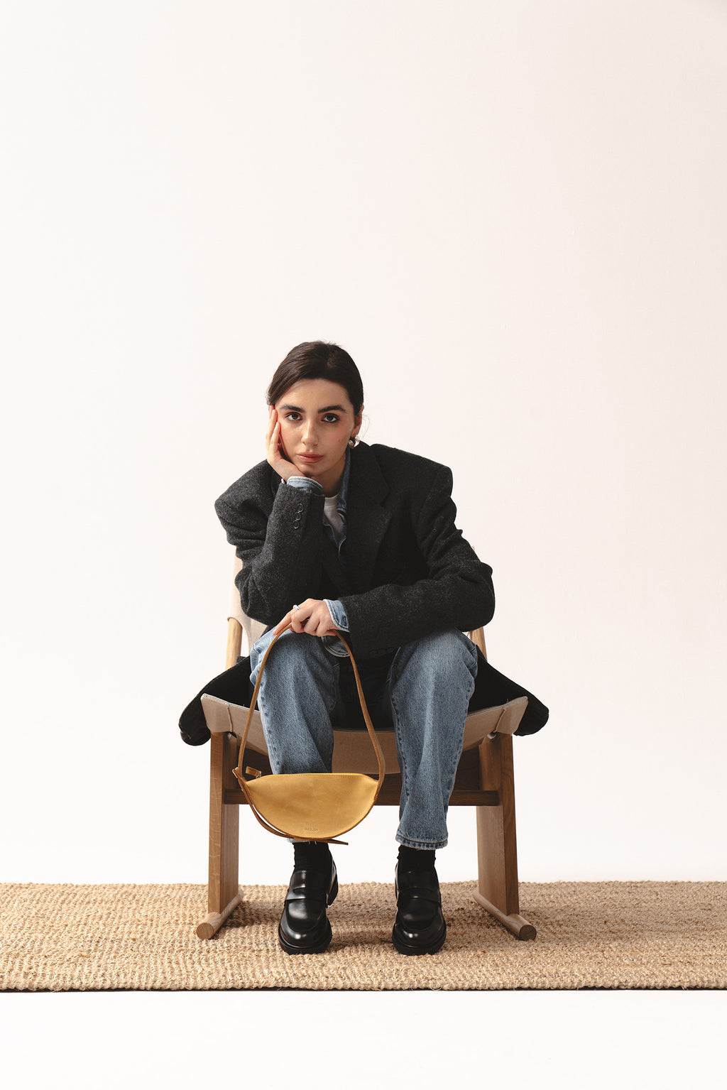 Żółta skórzana torebka Eclipse S marki Taksuba trzymana przez siedzącą kobietę